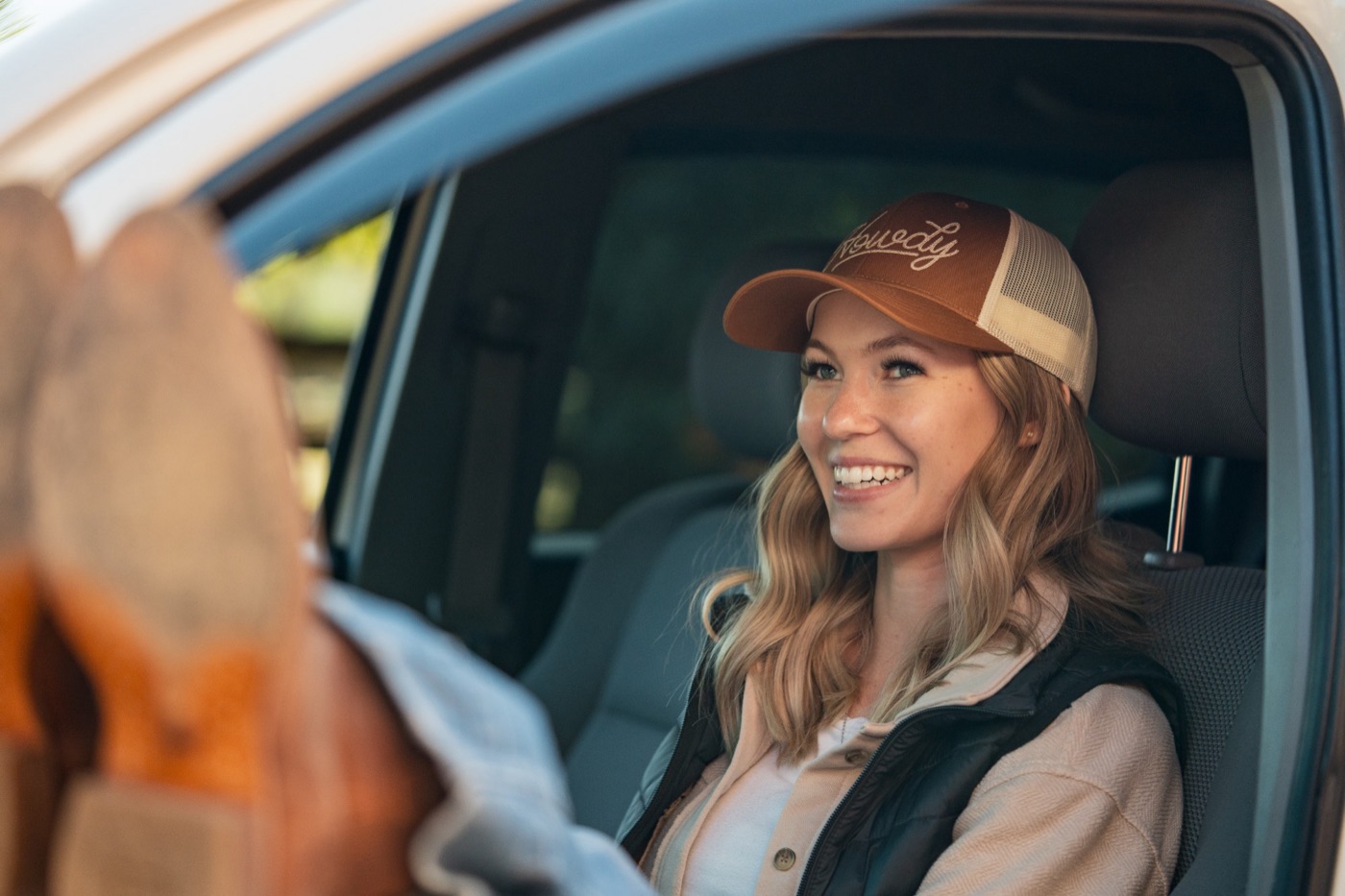 Smiling model in a Howdy cap in a truck cab
