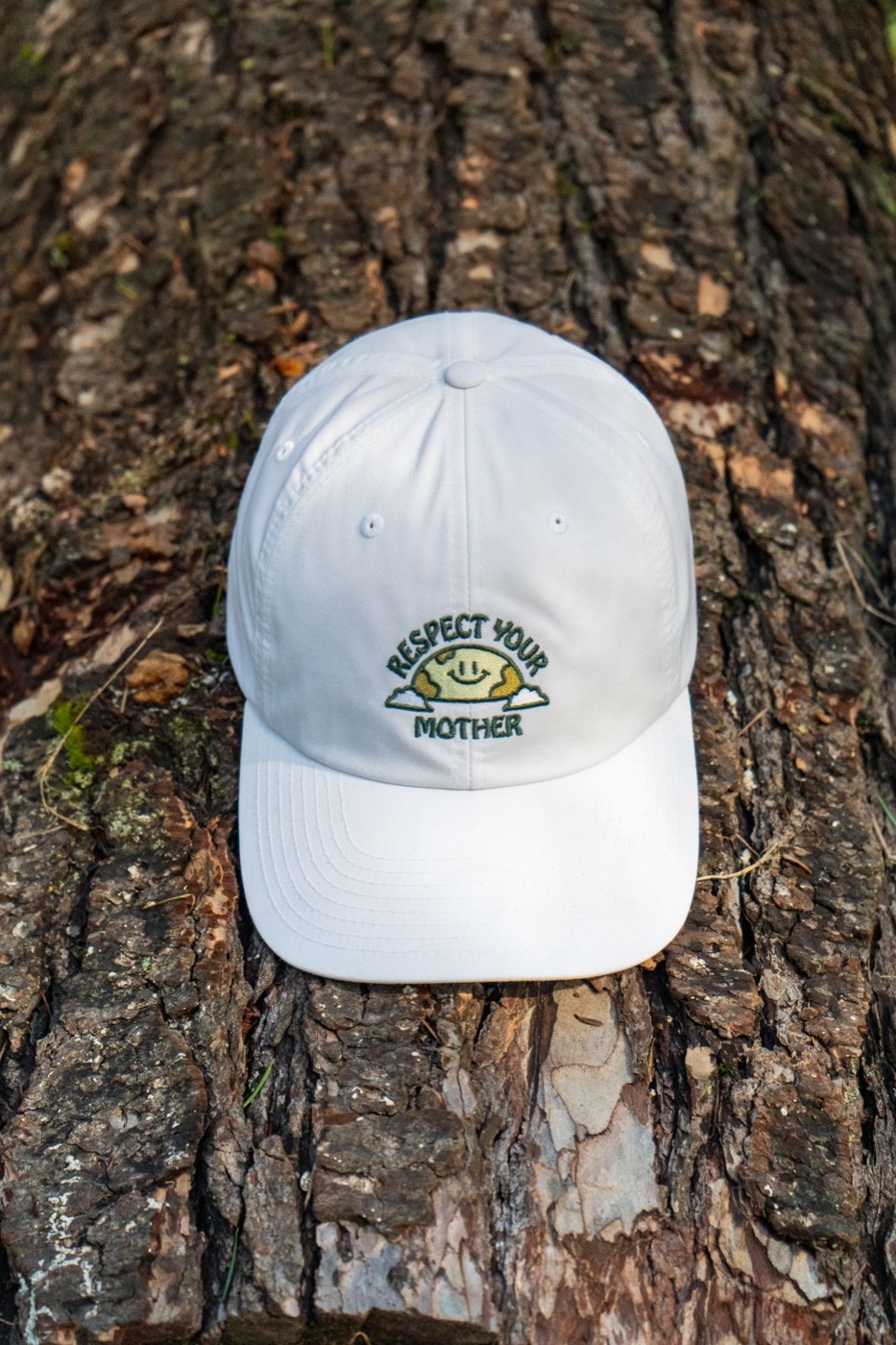 White Respect Your Mother cap resting on tree bark