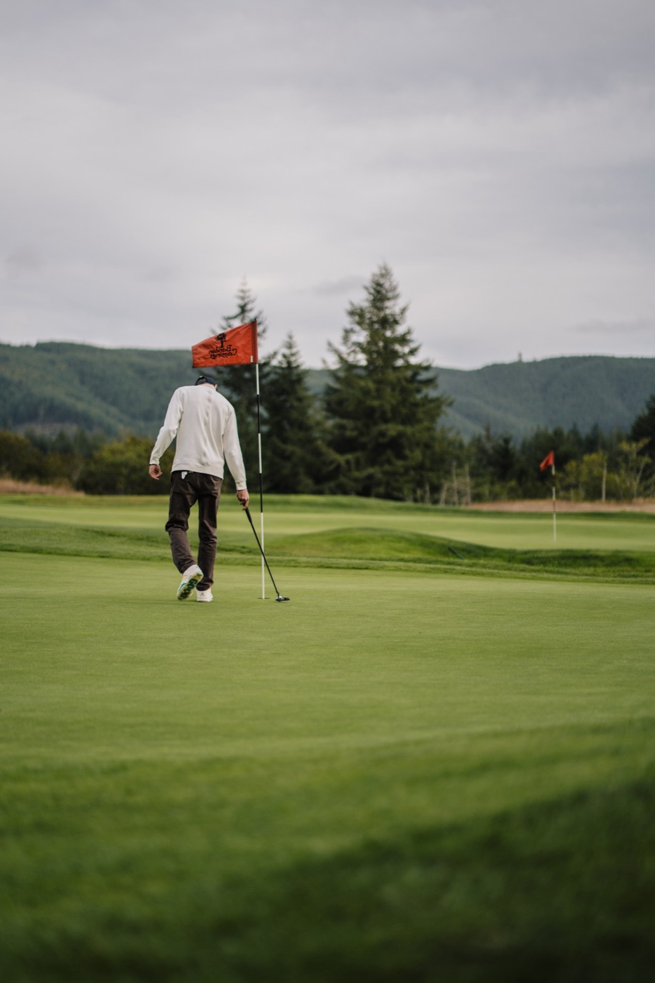Golfer walking off the green past the pin