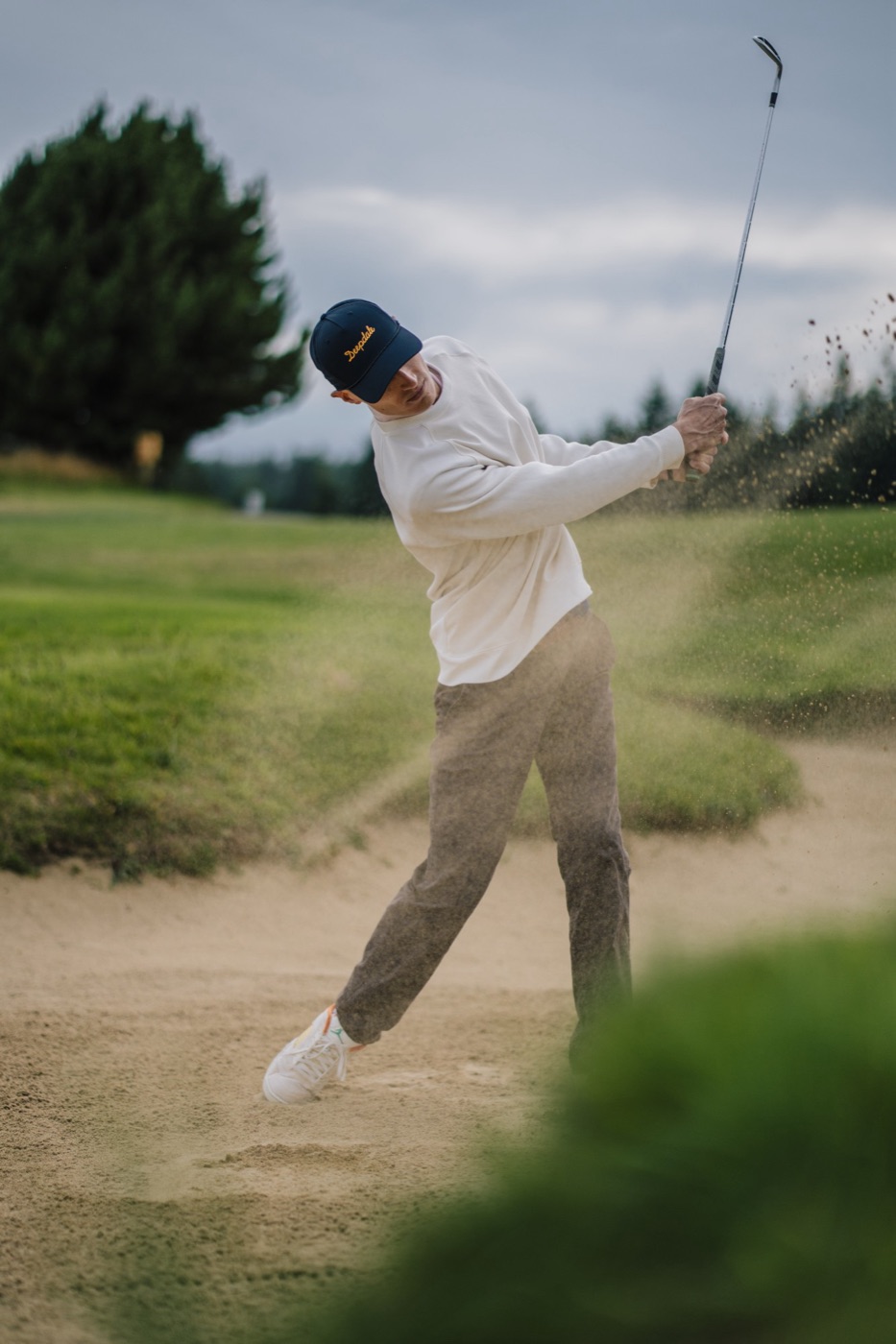 Golfer in a Deepdale cap blasting out of a bunker