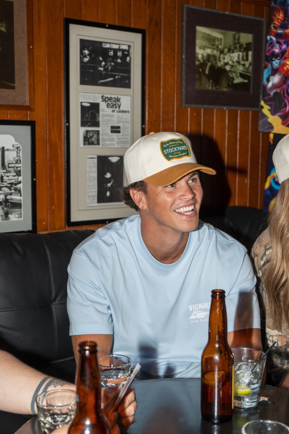 Smiling model in a Stockyard patch cap at a bar table