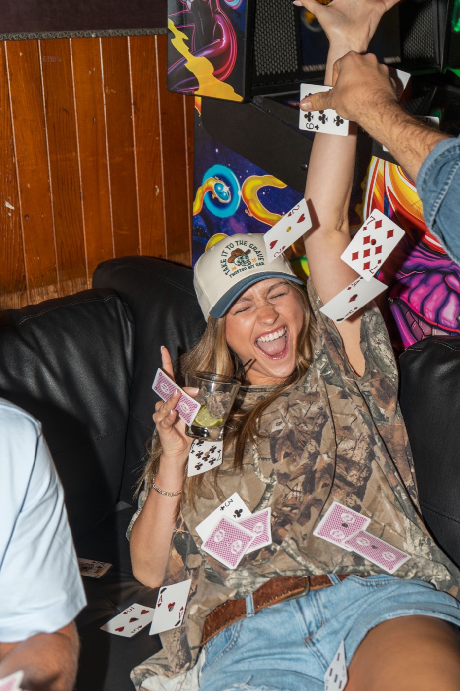 Model laughing as playing cards fly around her