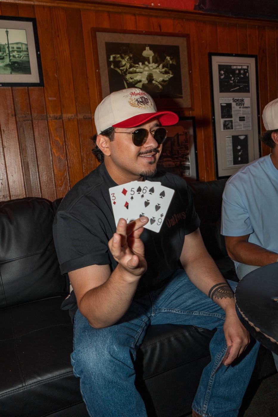 Model in a Montana cap and sunglasses showing his cards