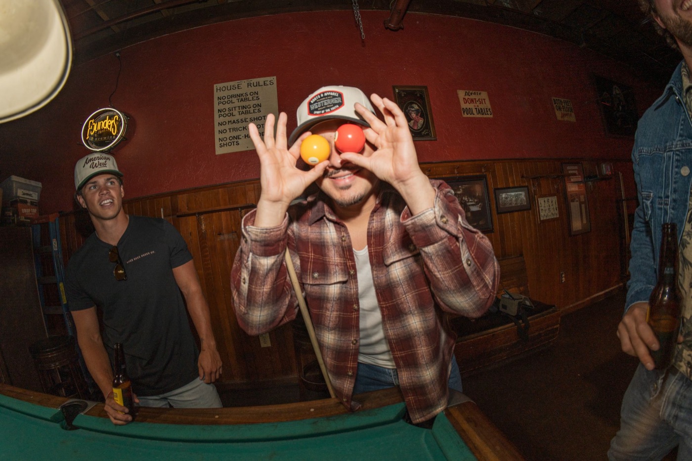 Model in a Westerner cap holding pool balls over his eyes