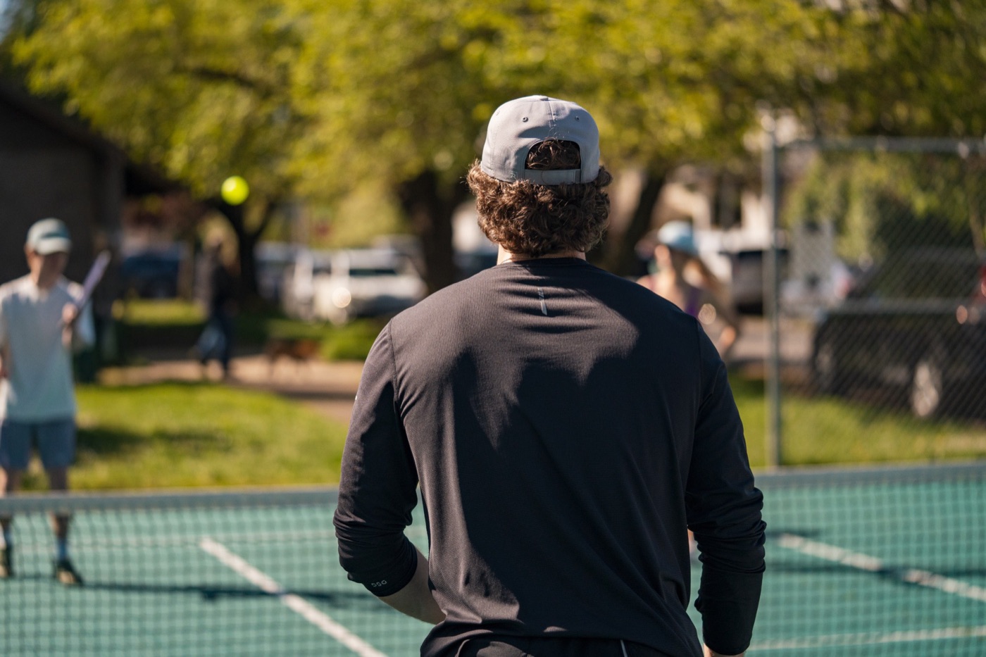 Player in a backwards cap watching a ball cross the net