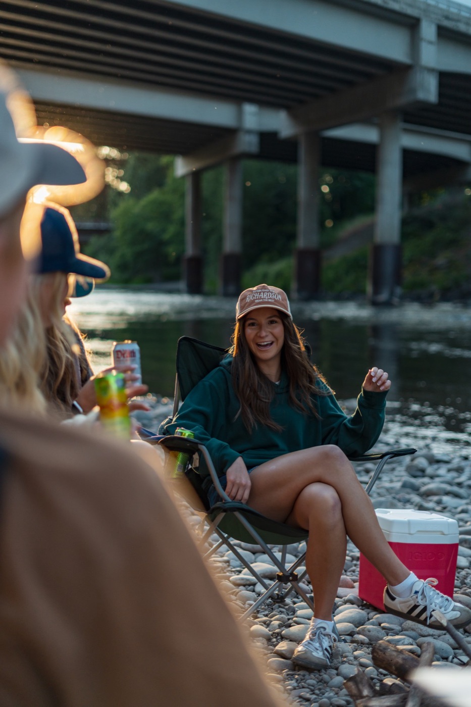 Woman in a Richardson trucker laughing in her camp chair by the water