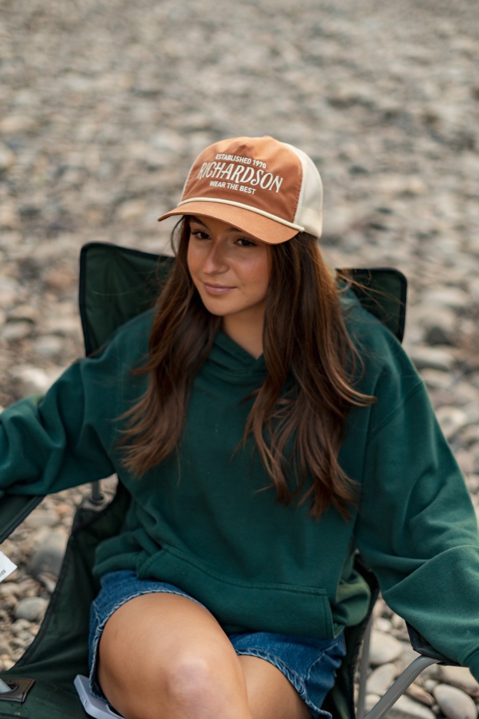 Woman in an orange Richardson Wear the Best trucker on the riverbank