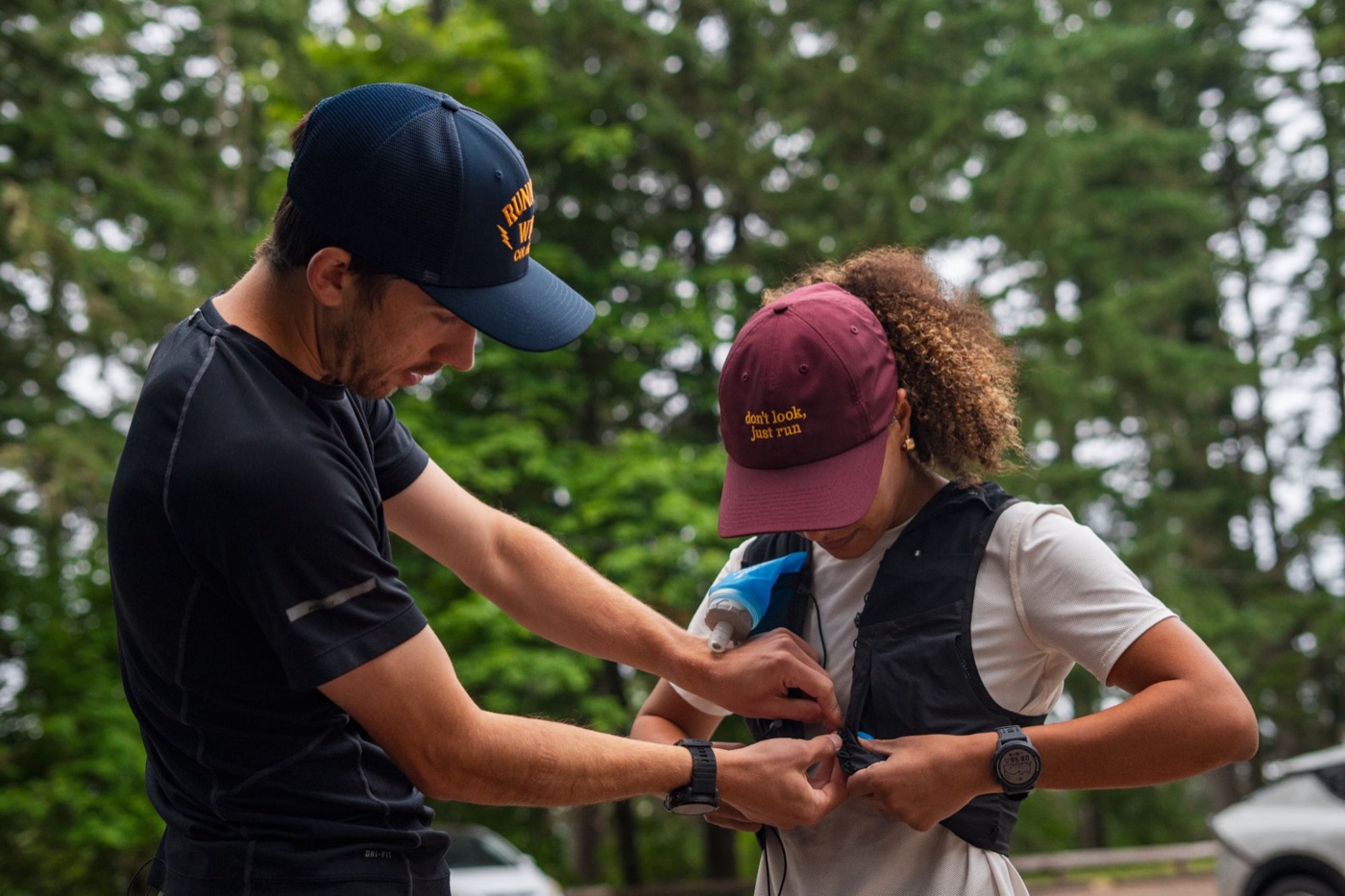 Two trail runners adjusting a hydration vest before a run