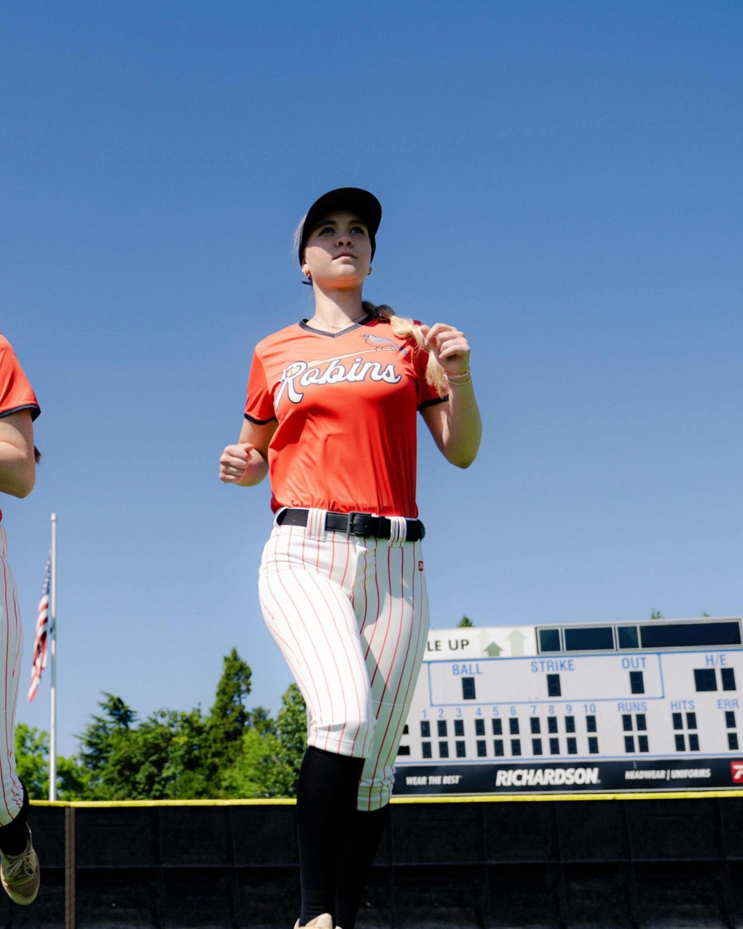 Softball player in a red jersey running toward the camera