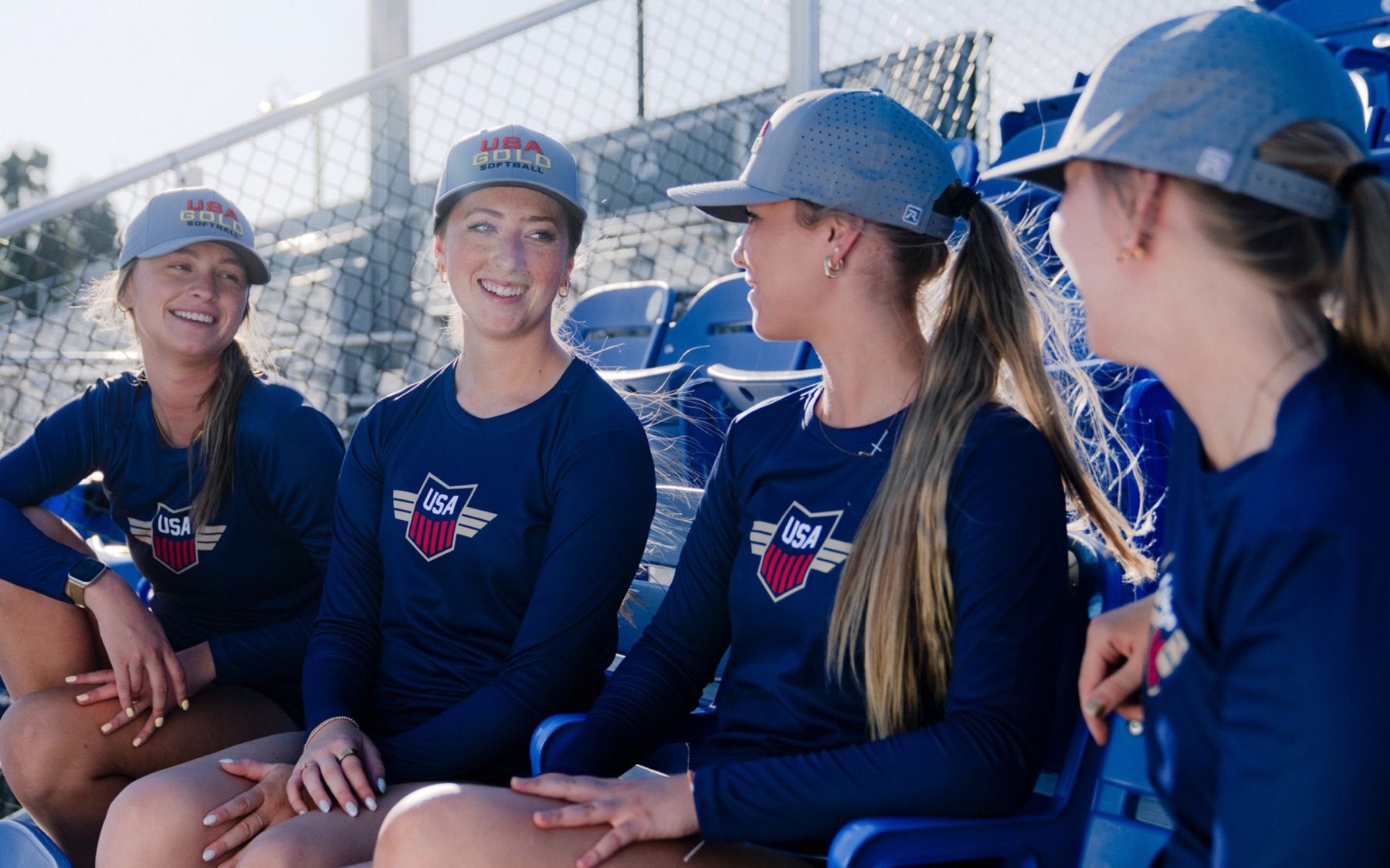 USA softball players in navy sitting together in the stands