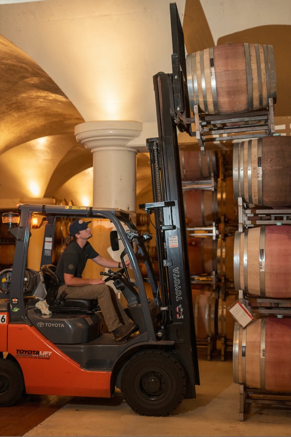 Cellar worker on a forklift lifting wine barrels